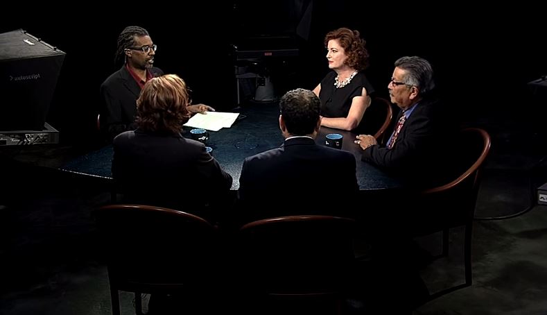 A group of people sitting around a table in a dark room.
