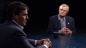 Two men sitting at a table talking to each other.