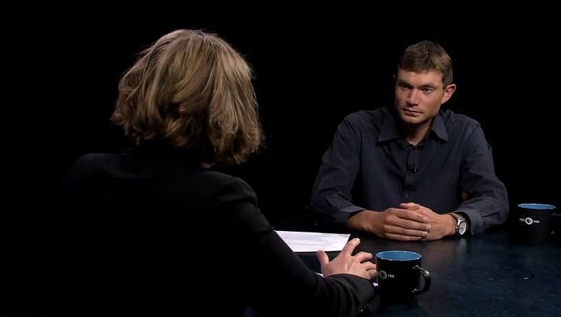 A man and woman sitting at a table talking.