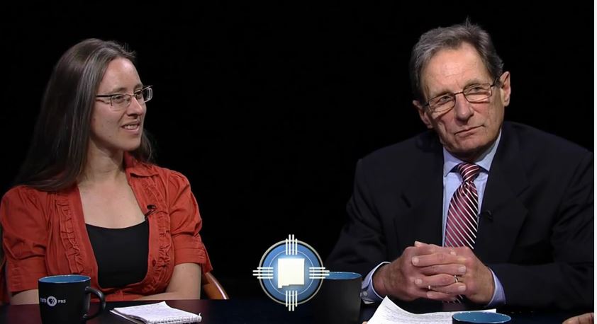 Two people sitting at a table talking to each other.