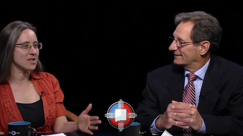 A man and woman sitting at a table talking.