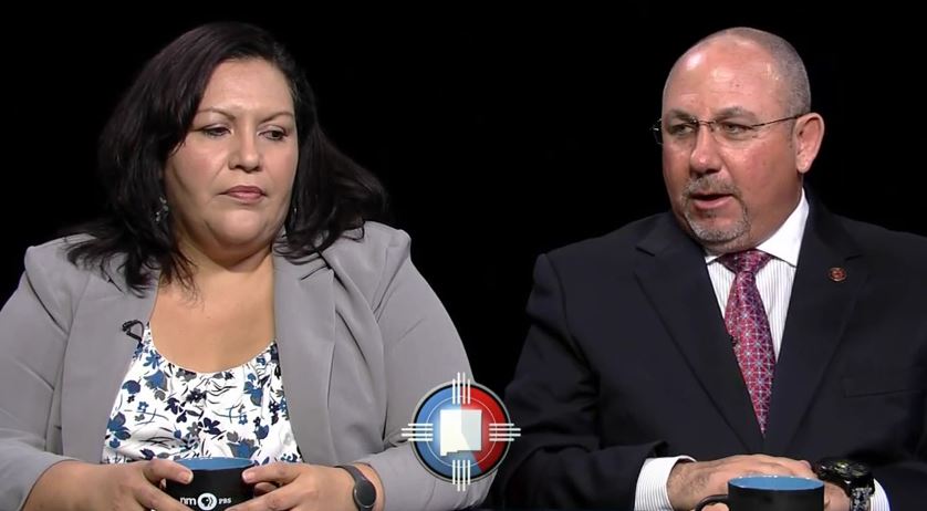 A man and woman sitting at a table with a cup of coffee.