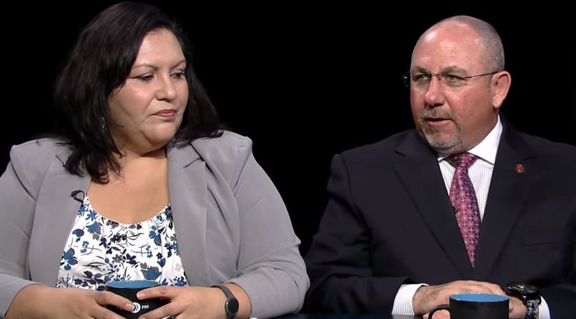 A man and woman sitting at a table with a cup of coffee.