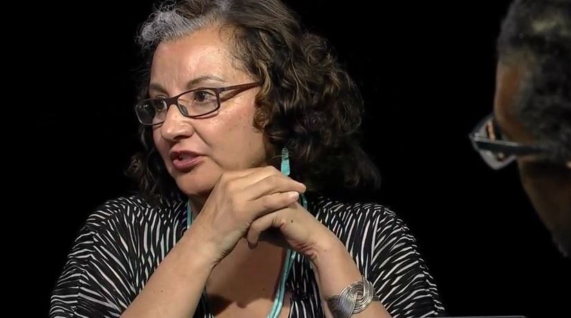 A woman in glasses is talking to a man.