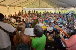 A crowd of people in a tent listening to music.