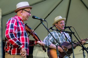 Two men in hats singing and playing instruments.