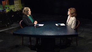 Two women sitting at a table in a television studio.