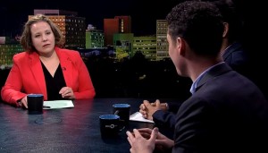 A man and woman sitting at a table in front of a city.