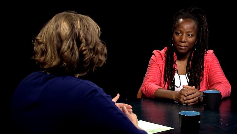 Two women sitting at a table talking to each other.