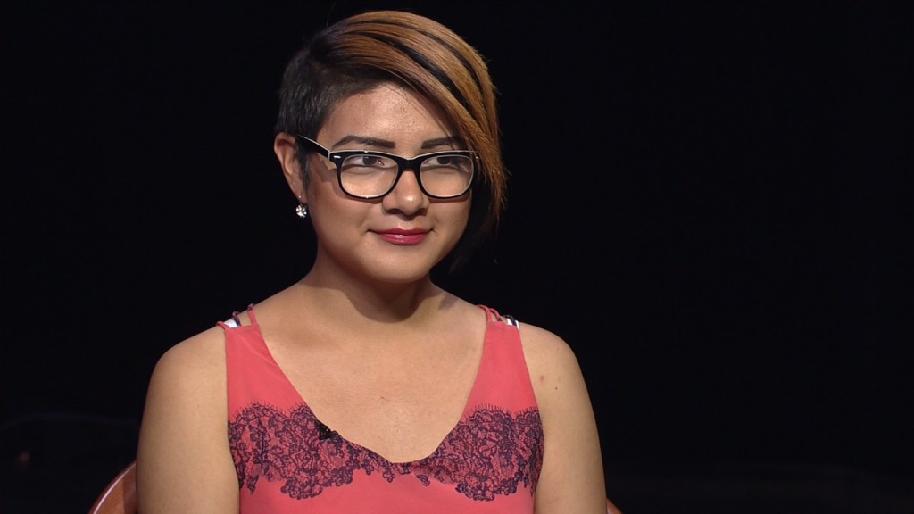 A woman wearing glasses and a pink dress.