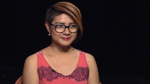 A woman wearing glasses and a pink dress.