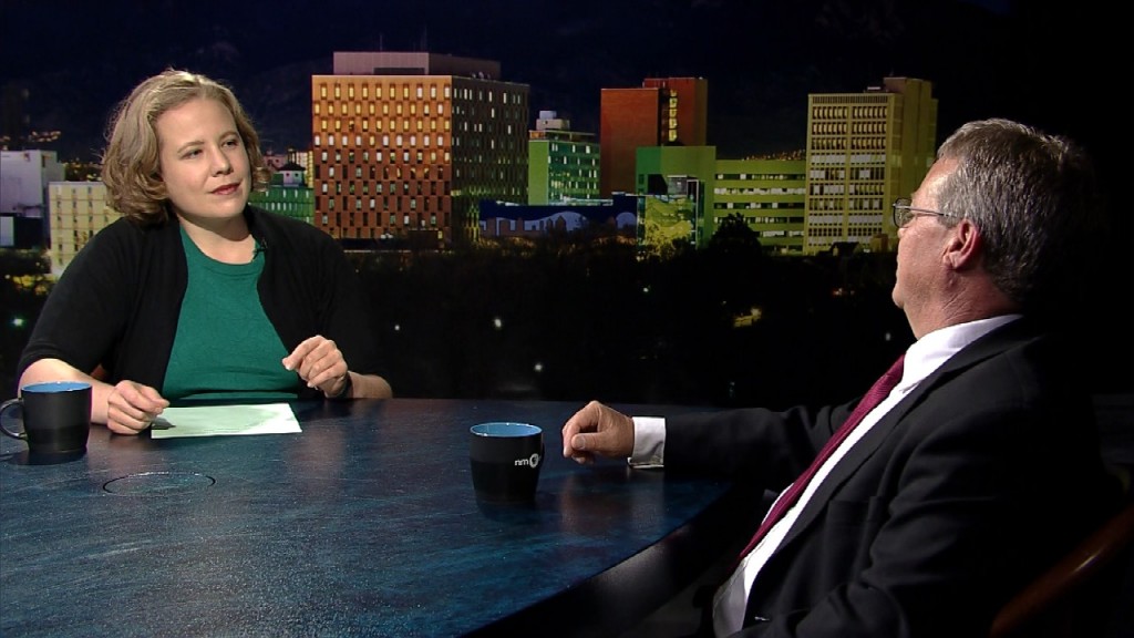 A man and woman sitting at a table in front of a city.