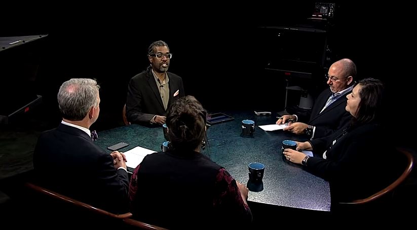 A group of people sitting around a table in a dark room.