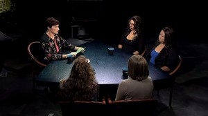 A group of women sitting around a table in a dark room.