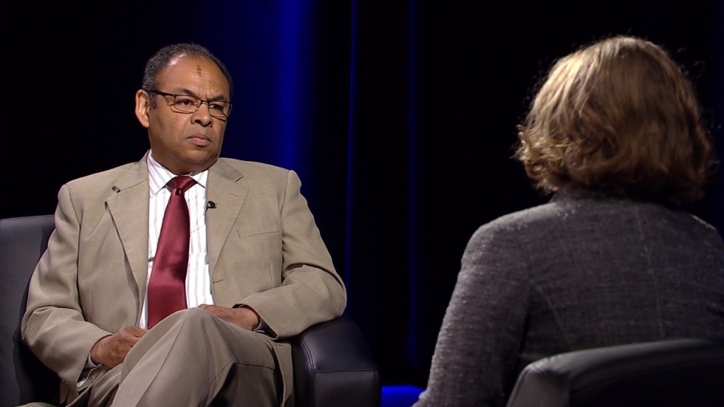 A man in a suit and tie is talking to a woman.