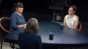 Three women sitting at a table talking to one another.