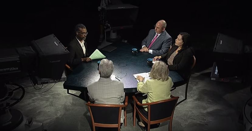 A group of people sitting around a table in a dark room.
