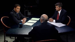 Three men sitting at a table in a dark room.