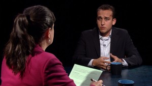 A man and woman sitting at a table talking to each other.
