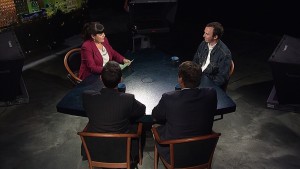 Three people sitting at a table in front of a screen.