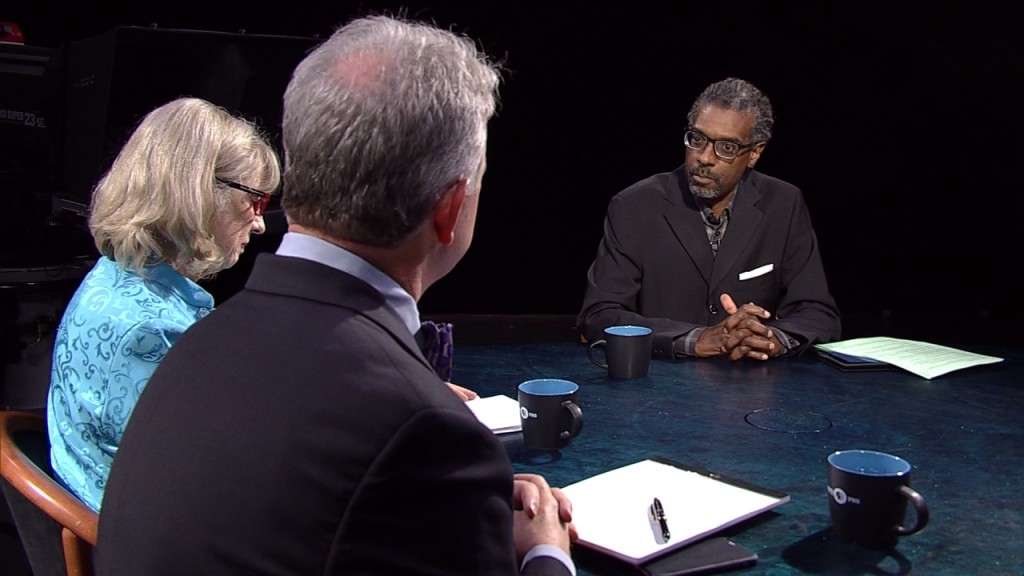 Three people sitting at a table talking to each other.