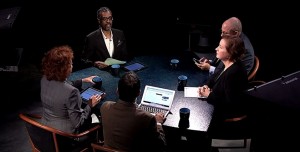 A group of people sitting around a table with laptops.