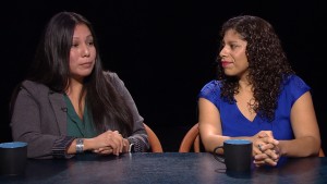 Two women sitting at a table talking to each other.