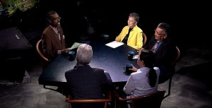 A group of people sitting around a table in a dark room.