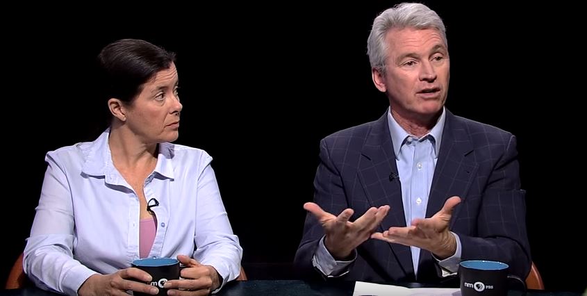 Two people sitting at a table talking to each other.