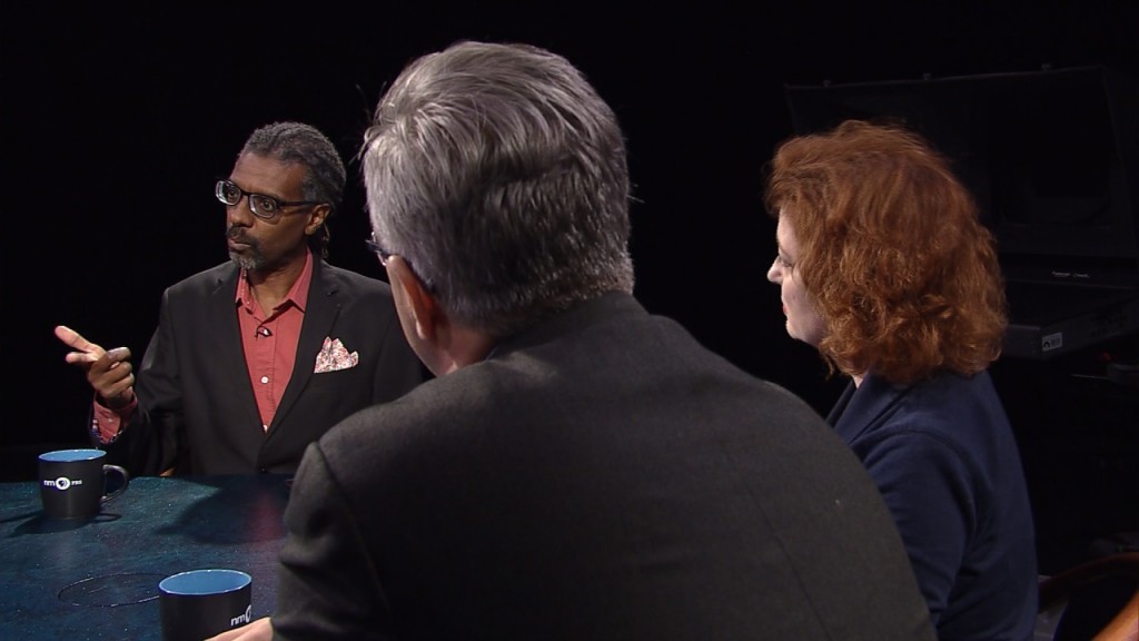 Three people sitting at a table talking to each other.