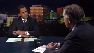 Two men sitting at a table in front of a city.