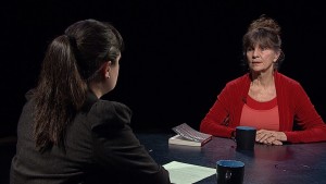 A woman sitting at a table with a book and a book.