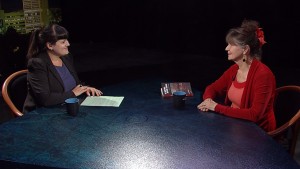 Two women sitting at a table talking to each other.