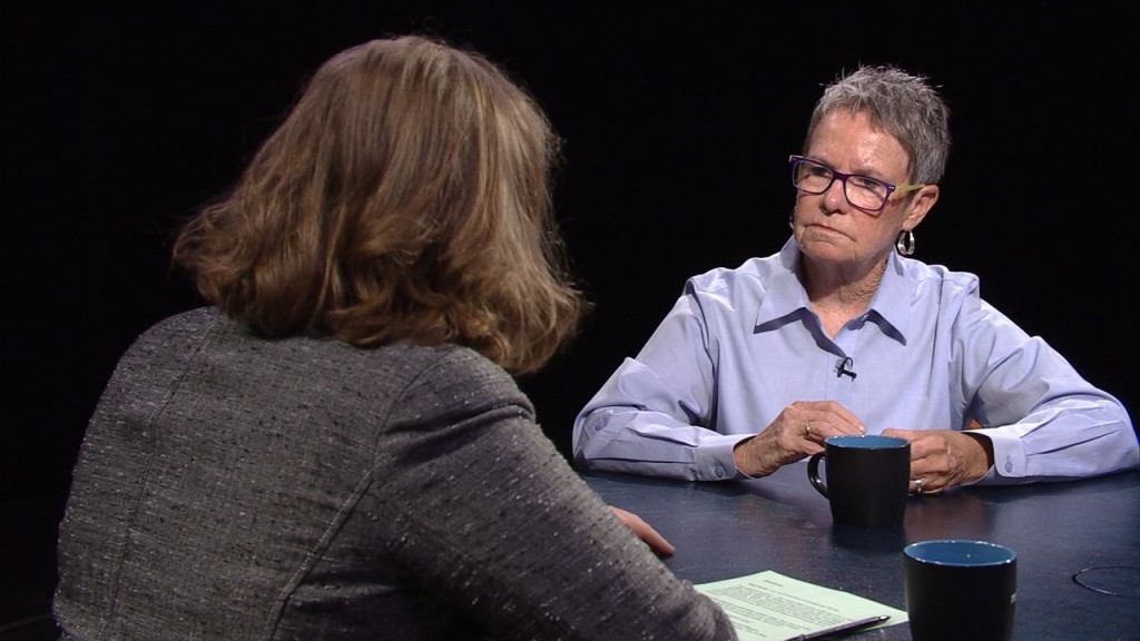 A woman sitting at a table with a woman in glasses.