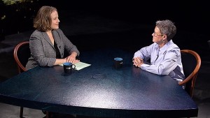 Two women sitting at a table talking to each other.