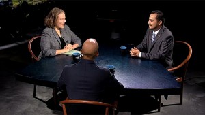 Three people sitting at a table talking.