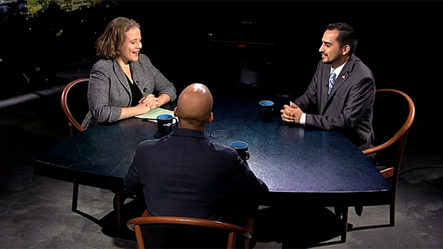 Three people sitting at a table talking.