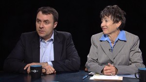 Two people sitting at a table with a cup of coffee.