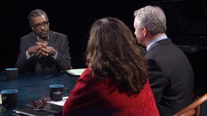 Three people sitting around a table talking to each other.