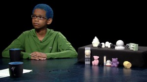 A young boy sits at a table with a cup of coffee.