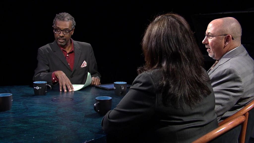 Three people sitting at a table talking to each other.