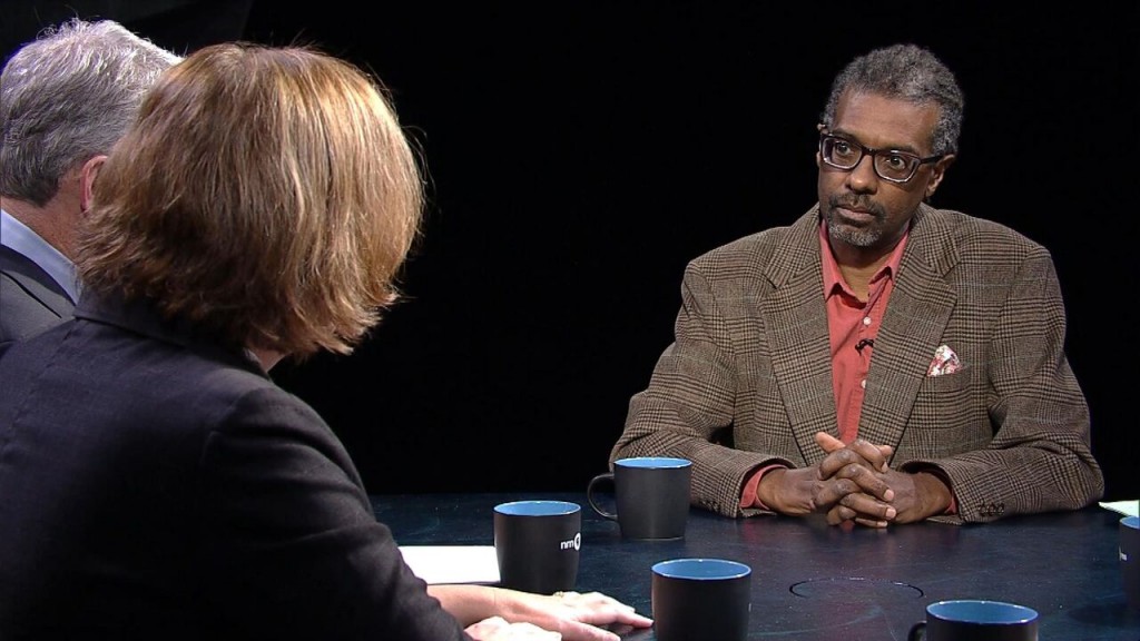 Three people sitting at a table talking to each other.