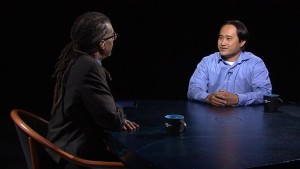 Two men sitting at a table talking to each other.