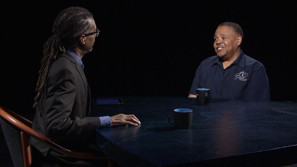 Two men sitting at a table talking to each other.