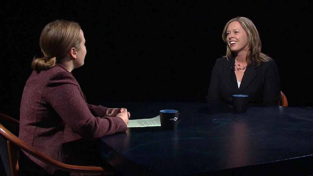 Two women sitting at a table talking to each other.