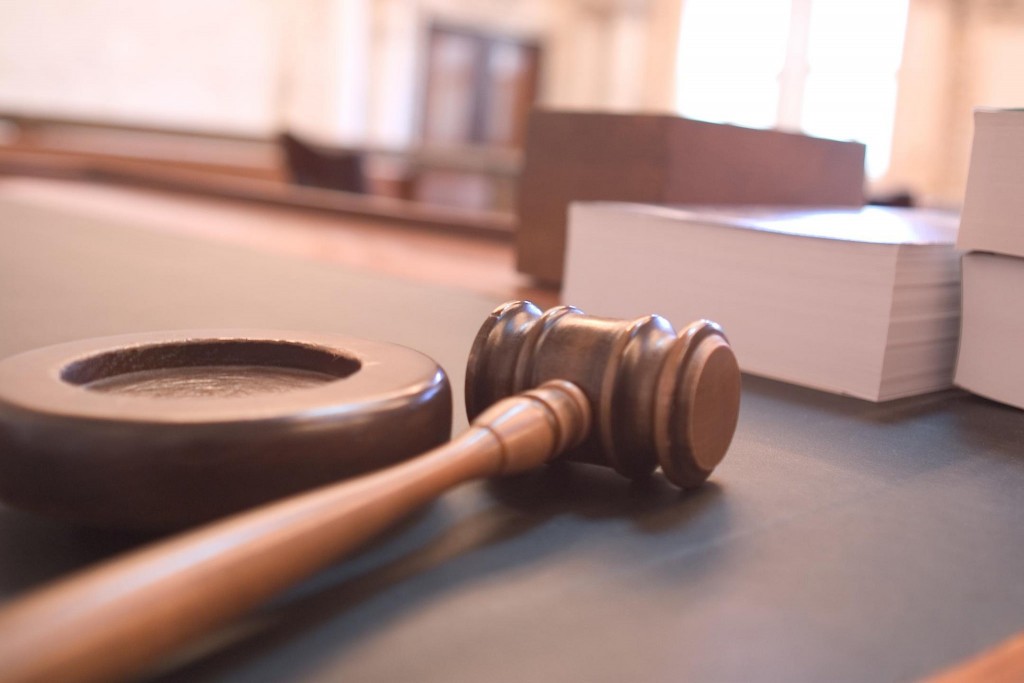 A judge's gavel sits on a table in a courtroom.