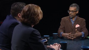 Three people sitting at a table talking to each other.