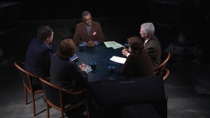 A group of people sitting around a table in a dark room.