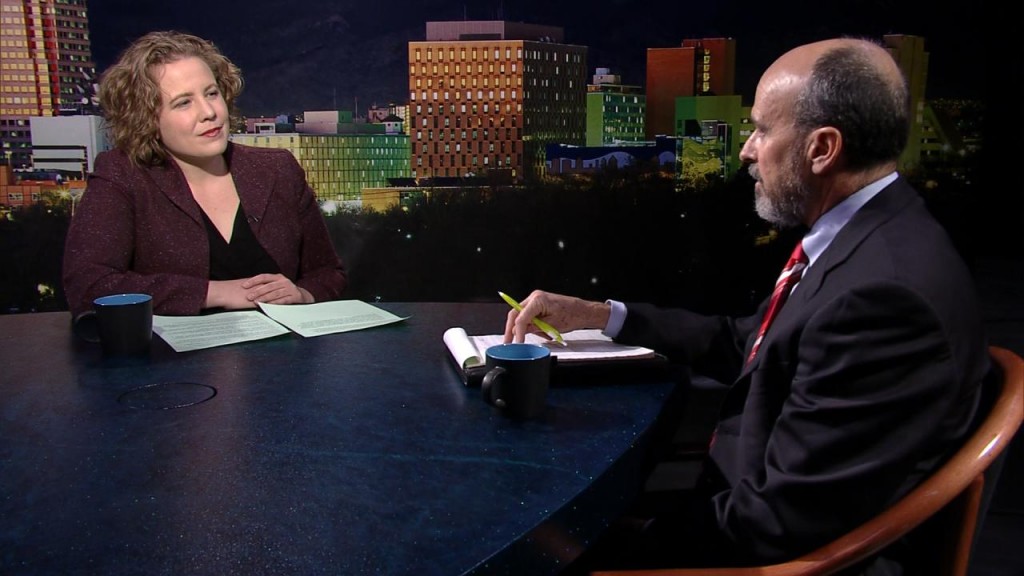 A man and woman sitting at a table in front of a city.