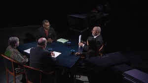 A group of people sitting around a table in a dark room.